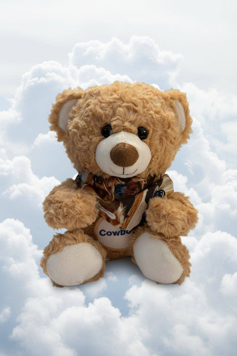 Brown teddy bear with a 'Cowboy' shirt sitting in the snow