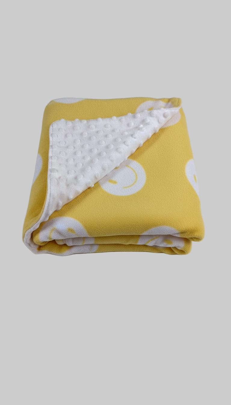 Yellow fabric with white smiley face patterns and white minky dot material on the back