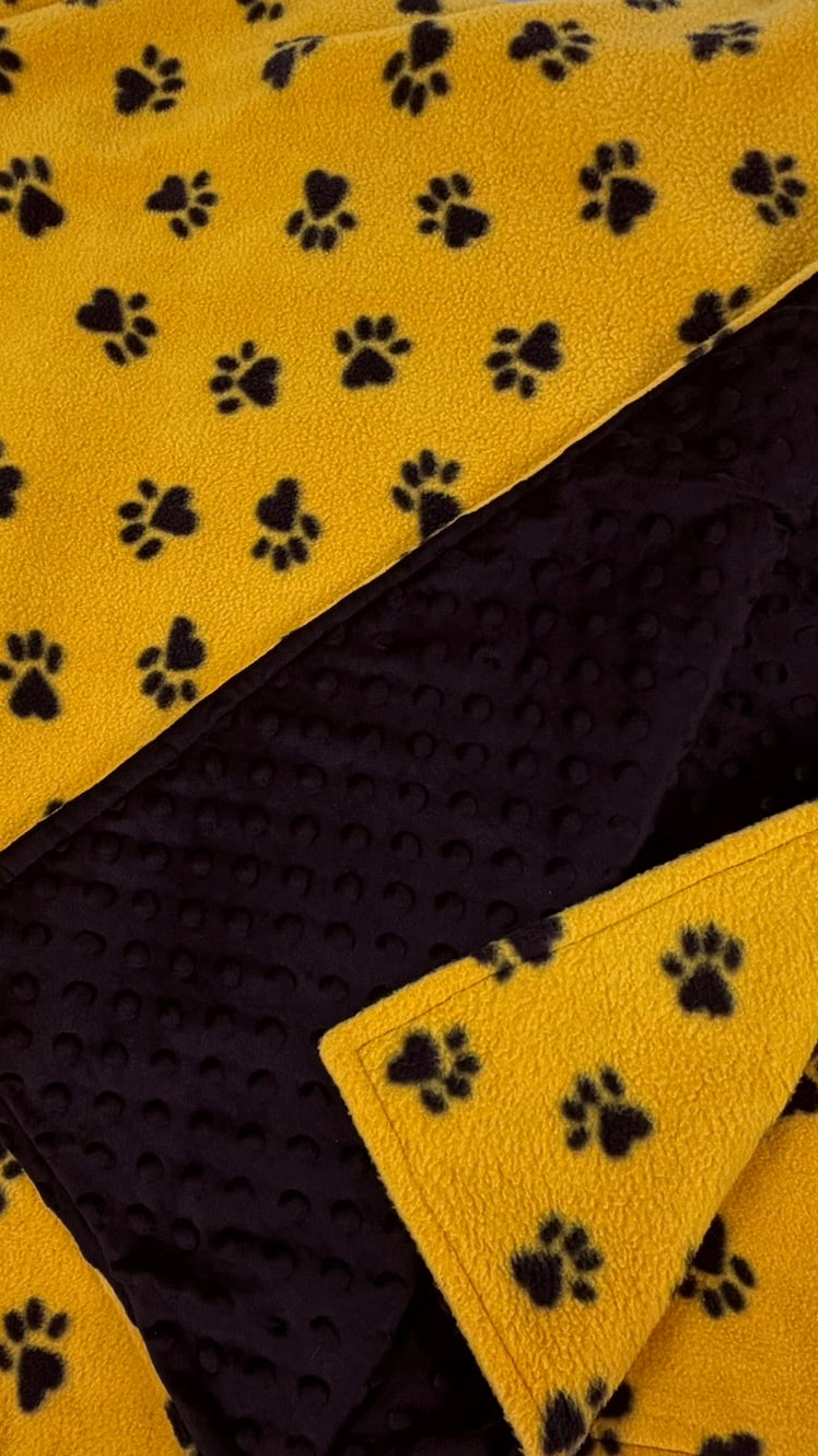 Yellow blanket with black paw prints on a white background